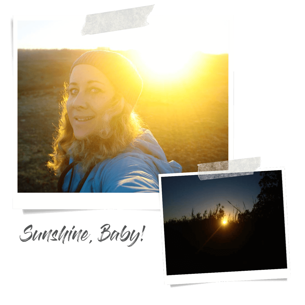 Frau mit dicker Jacke und Beanie steht auf einem Feld und schaut in die Kamera, während hinter ihr die Sonne aufgeht.