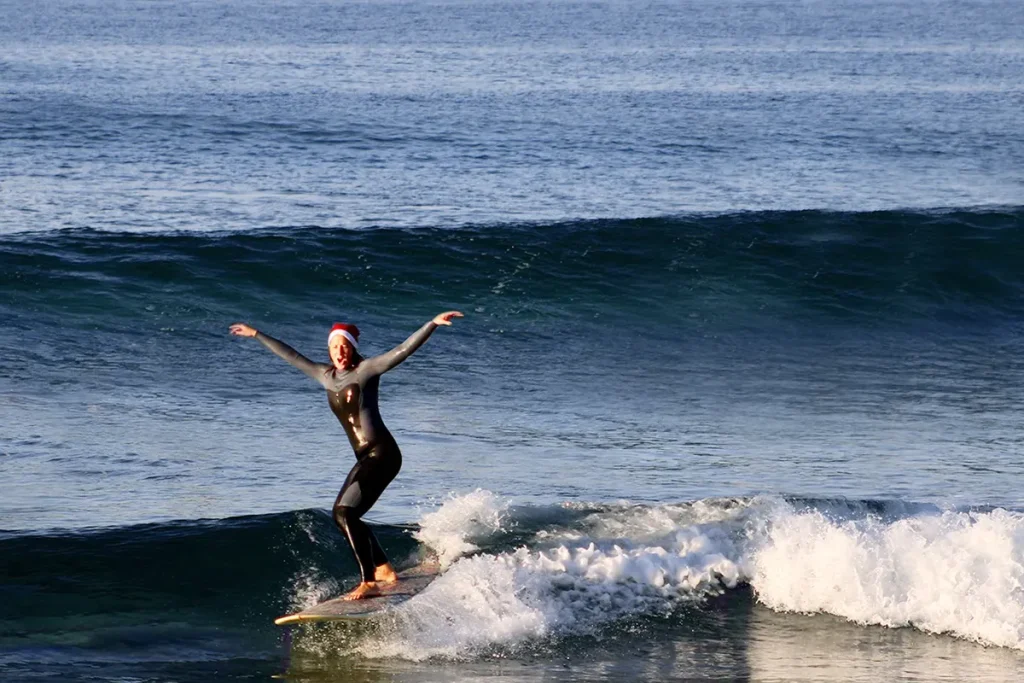 Britta surft mit Nikolausmütze ein Longboard.