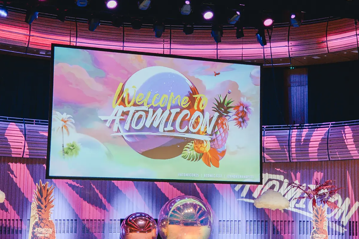 Die pink erleuchtete Bühne der Atomicon 2025 mit dem Screen, der "Welcome to Atomicon" zeigt.