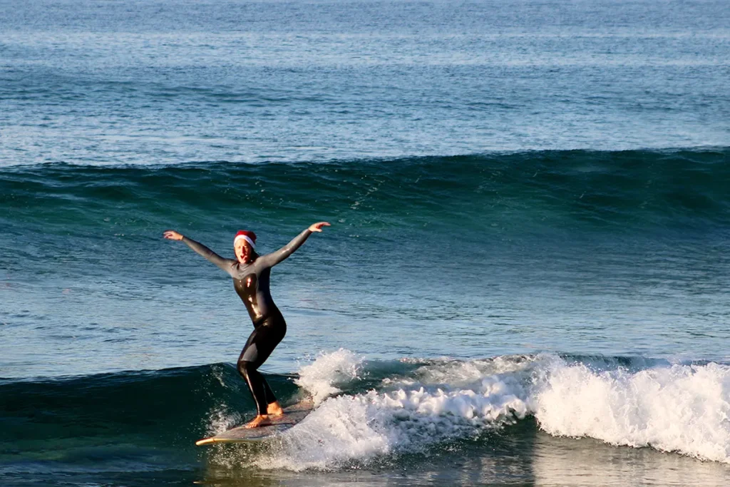 Britta mit Nikolausmütze surft eine Welle auf ihrem Longboard.