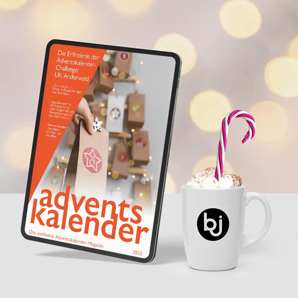 Tabklet mit dem Cover des Adventskalender Magazin 2025 auf dem Screen, daneben eine Tasse Kakao mit Zuckerstange.