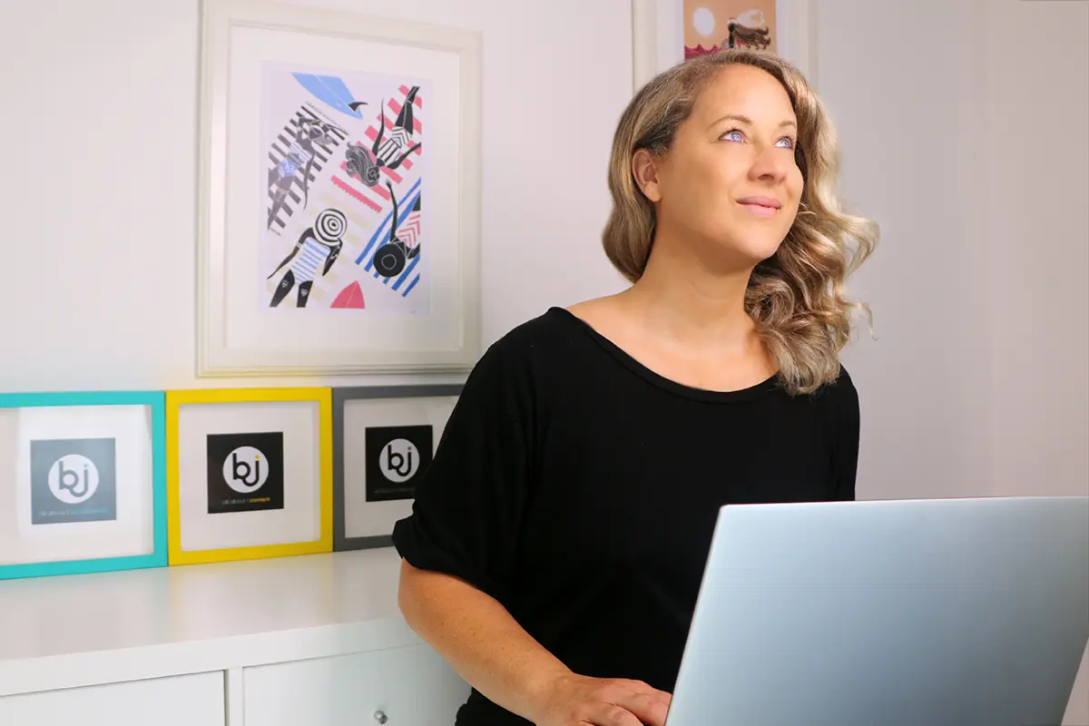 Britta sitzt tippend an ihrem Laptop und schaut in Gedanken nach oben, währen sie über ihre Blogstatistik 2025 nachdenkt.