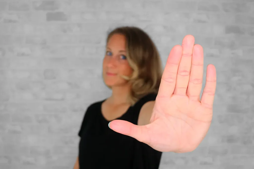 Britta hält die Handfläche in die Kamera als Symbol für "Bye-bye Ja-zu-jedem: Warum ich Businessanfänger:innen keine Websites mehr verkaufe".